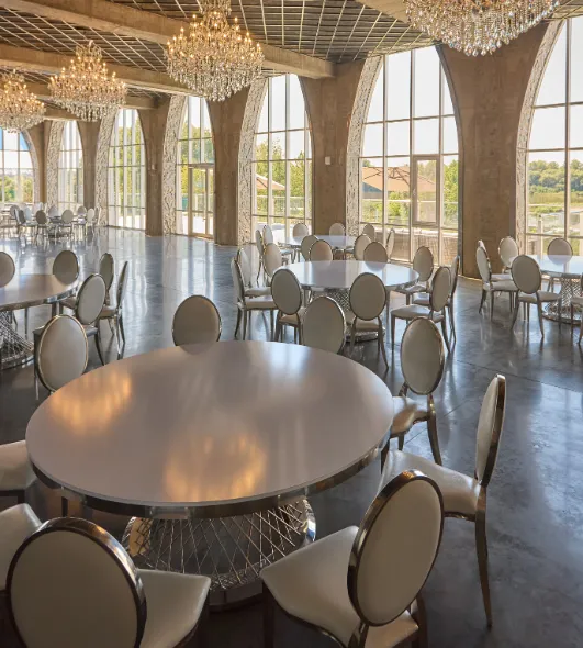 Elegant event hall interior design in Dallas featuring crystal chandeliers, arched windows, and round banquet tables